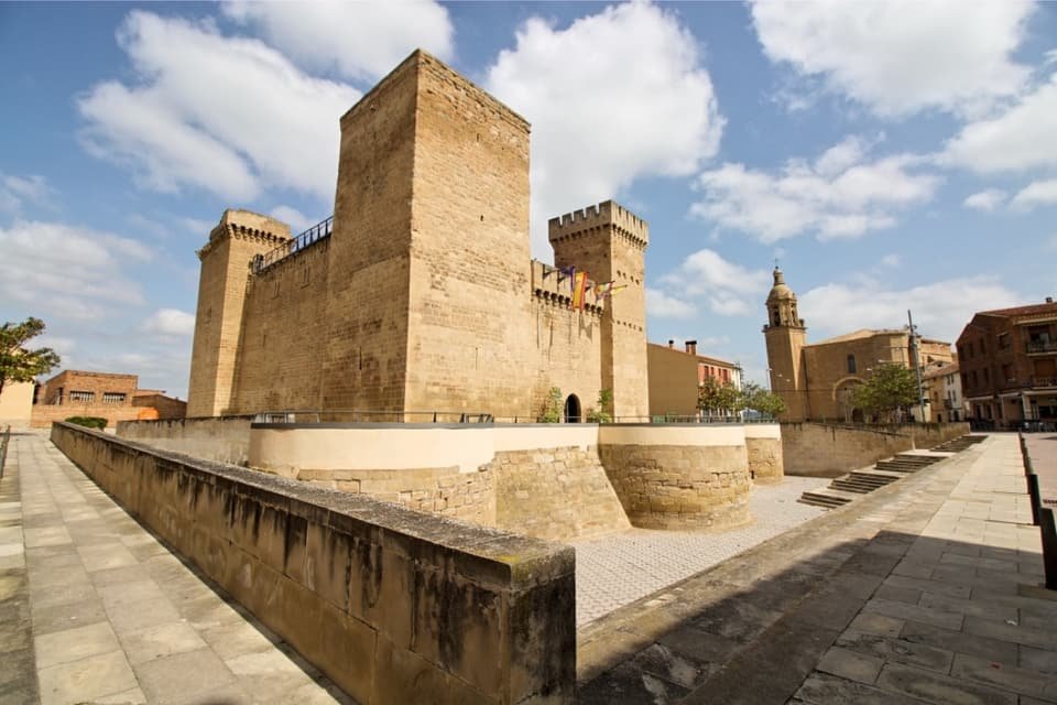 Aguas Mansas Castle in Agoncillo, with its stone towers and the church tower behind