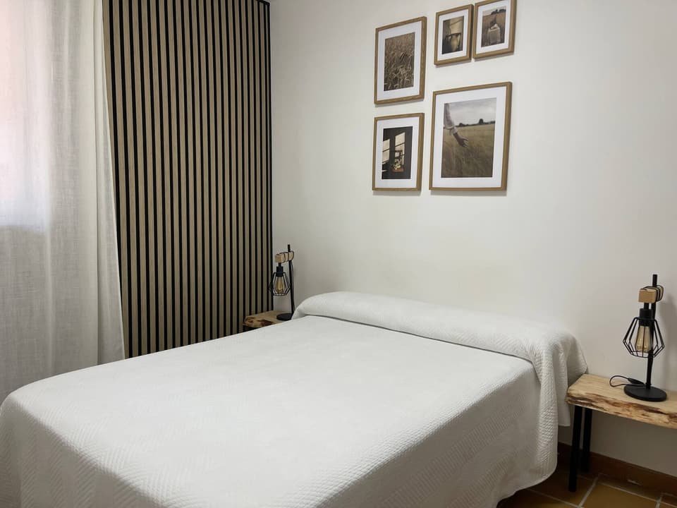 Casa B bedroom with double bed, slatted wood panel and framed prints