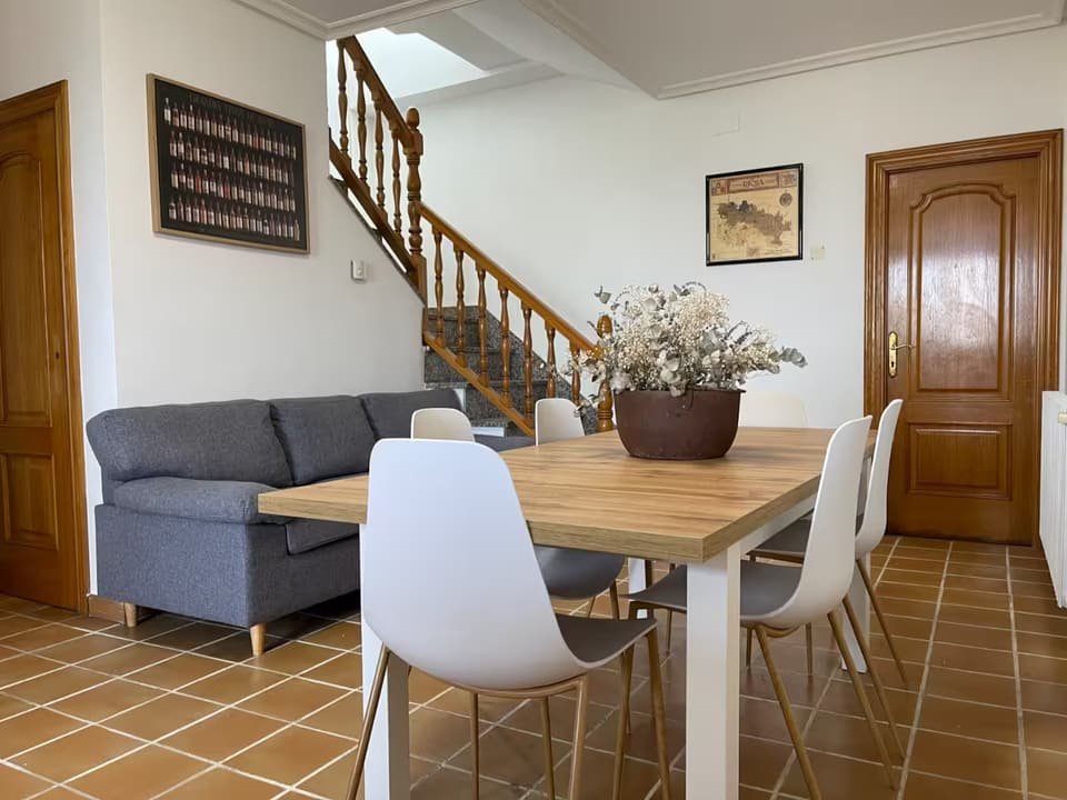 Casa B living-dining room with sofa and wooden staircase